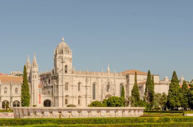 Collonges-la-Rouge 'daki tarihi mimarinin pitoresk bir görüntüsü, karmaşık Gotik detaylarla dolu büyük bir katedrali gösteriyor. Görüntü, şehrin dingin güzelliğini, berrak mavi bir gökyüzünün altında, zamansız cazibesini ve kültürünü yansıtıyor.