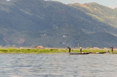 Arka planda ikonik Asılan Manastır olan göldeki balıkçıların huzurlu görüntüsü. Sahne, bereketli dağlar ve sakin sular tarafından çerçevelenmiş geleneksel Çin yaşamının sükunetini yakalıyor. Huzur ve uyumu çağrıştırıyor..