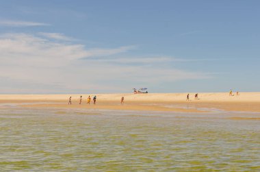 Arcachon Körfezi, Fransa 'da canlı ve sakin bir plaj sahnesi, güneşli bir günün keyfini çıkaran insanları gösteriyor. Görüntü, açık mavi gökyüzü, yumuşak dalgalar ve geniş bir altın kum tabakasıyla yazın özünü yakalar. Seyahat ve eğlence temaları için ideal.