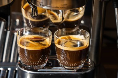 Ön tarafta iki bardak taze demlenmiş klasik espresso kahvesi var.