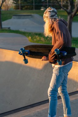 Kaykaycı kadın kaykaycı gün batımında kaykay parkındaki yarım boru rampasında ışığa karşı.