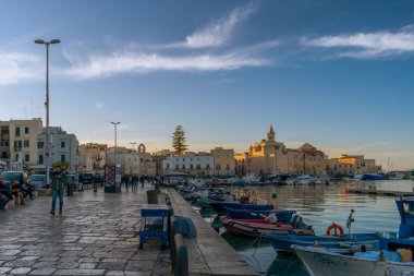 Gün batımında Trani limanının panoramik manzarasında balıkçı tekneleri, balıkçı tekneleri ve San Nicola Pellegrino Bazilikası var. Puglia, İtalya.
