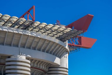 Milano 'daki San Siro Stadyumu (Giuseppe Meazza), İtalya' nın Lombardy kentinin mimari bir ikonu olan mavi gökyüzü altında sarmal sütunlar ve kırmızı geçitlerle