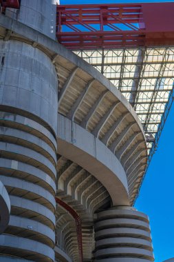 Milano 'daki San Siro Stadyumu (Giuseppe Meazza), İtalya' nın Lombardy kentinin mimari bir ikonu olan mavi gökyüzü altında sarmal sütunlar ve kırmızı geçitlerle