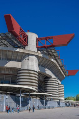 Milano 'daki San Siro Stadyumu (Giuseppe Meazza), İtalya' nın Lombardy kentinin mimari bir ikonu olan mavi gökyüzü altında sarmal sütunlar ve kırmızı geçitlerle
