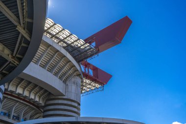 Milano 'daki San Siro Stadyumu (Giuseppe Meazza), İtalya' nın Lombardy kentinin mimari bir ikonu olan mavi gökyüzü altında sarmal sütunlar ve kırmızı geçitlerle