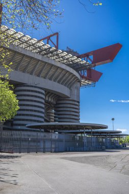 Milano 'daki San Siro Stadyumu (Giuseppe Meazza), İtalya' nın Lombardy kentinin mimari bir ikonu olan mavi gökyüzü altında sarmal sütunlar ve kırmızı geçitlerle