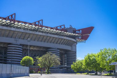 Milano 'daki San Siro Stadyumu (Giuseppe Meazza), İtalya' nın Lombardy kentinin mimari bir ikonu olan mavi gökyüzü altında sarmal sütunlar ve kırmızı geçitlerle