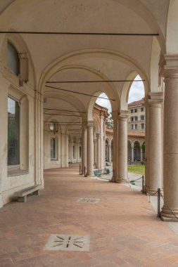 Milano 'nun göbeğinde bir barok manastırı olan Rotonda della Besana' nın kemerli porticosu (Lombardy), İtalya tarihsel sütunları ve yumuşak ışıklı bir günde şehir bahçesi.