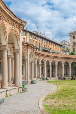 Milano 'nun göbeğinde bir barok manastırı olan Rotonda della Besana' nın kemerli porticosu (Lombardy), İtalya tarihsel sütunları ve yumuşak ışıklı bir günde şehir bahçesi.