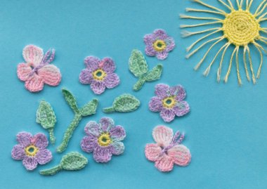 Aquamarine arka planında örülmüş ürünlerin bir kompozisyonu var. Çiçekli, kelebekli ve güneşli bir bahar ya da yaz gününün taklidi. Harika sıcak ve güneşli hava