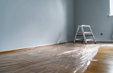 Duvarı boyamak için onarım ya da hazırlık. Zemin film, çalışma aletleri ve merdiven ile kaplı. Mesaj için yer var. Çizgileri korumak için bant maskeleme