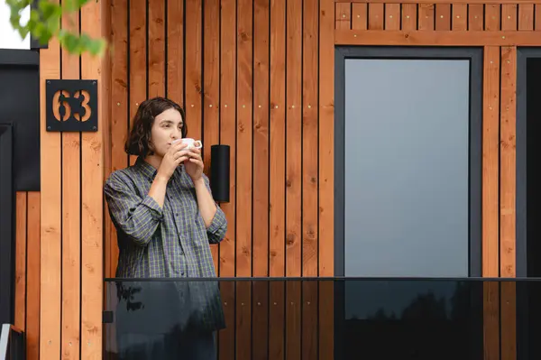 Kız balkonda dururken kahve ya da çay içer. Kadınlar modern otel tatil beldesinde tatilin tadını çıkarıyorlar. Yalnızlık ve doğada eğlence kavramı.