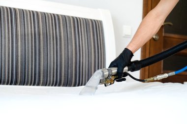 Temizlik konsepti. Adam yatak odasını temizler, kapatır. Virüs önleme içeride dezenfekte ediliyor. Mobilya temizleme işlemi. Profesyonel kimyasal temizlik..