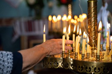 Yaşlı bir kadının eli. Mum alevi. Bir şamdanda bir sürü sarı mum. Kilise ya da tapınaktaki kutsal ayin..