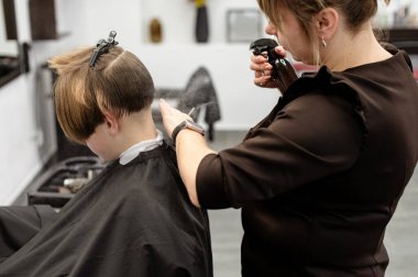 Bir kuaför zarif bir kuaförde müşterinin saç stilini dikkatlice düzeltir. Atmosfer çağdaş, profesyonel kuaför aletleri ve ekipmanları sergiliyor..