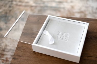 İyi yapılmış bir hediye kutusu ahşap bir masada oturur ve içinde aşk kelimesinin hassas bir yazısıdır. Dekor sıcak ve davetkar bir atmosferi ön plana çıkarıyor, özel durumlar için mükemmel..