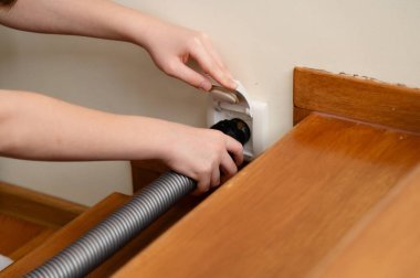 Bir genç, ev ödevlerini ve sorumluluklarını elektrikli süpürge kullanarak dengeliyor. Ahşap merdivenleri olan sıcak ve davetkar bir yer..