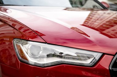 Ivano-Frankivsk, Ukrayna 12 Ekim 2023: Aydi A6 arabası, sedan. Kırmızı bir A6 'nın detaylı bir yakın çekimi, parlak tasarımını ve modern özelliklerini vurguluyor. Civardaki binaların yansımaları parlak yüzeyine yansıyarak kentsel çevresini vurguluyor.