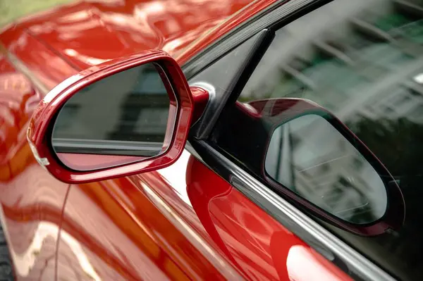 Ivano-Frankivsk, Ukrayna 12 Ekim 2023: Aydi A6 arabası, sedan. Kırmızı bir A6 arabanın yan aynasının modern siluetini ve canlı rengini göstermesi. Çevredeki binaların yansımaları arabanın tasarımını şehir ortamında tamamlıyor..