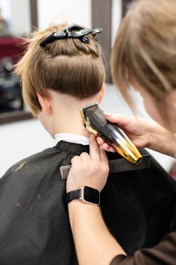 Bir stilist modern bir kuaförde bir müşterinin saçını kesmek için makas kullanır. Atmosfer sakin, aynalar düzeni yansıtıyor..