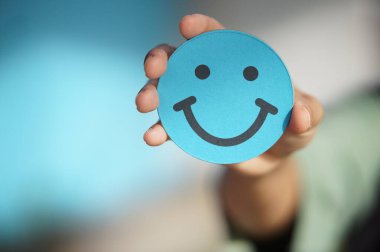 Küçük kavisli bir el tutarken yakın plan. Kağıt ya da kartın gülen yüzü.