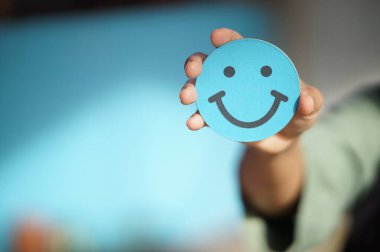 Küçük kavisli bir el tutarken yakın plan. Kağıt ya da kartın gülen yüzü.