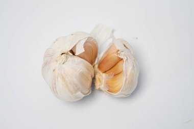 Beyaz bir zemin üzerinde taze sarımsak soğanları ve karanfiller sergileniyor..