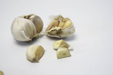 Beyaz bir zemin üzerinde taze sarımsak soğanları ve karanfiller sergileniyor..