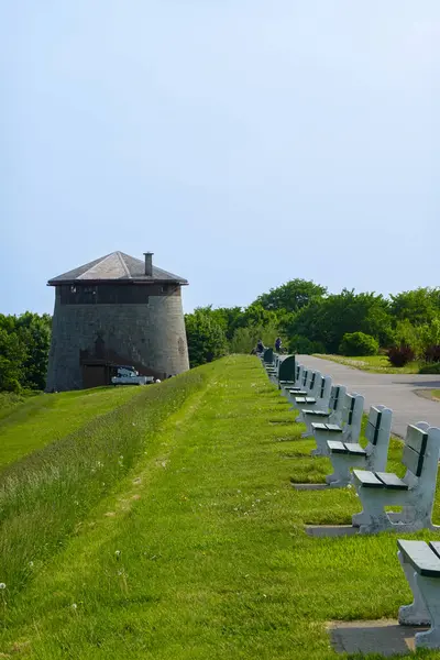 Tarihi silindirik taş kule ya da kırsal yolun yanındaki istihkam. Kırsal alanda duran yıpranmış taş işçilikli geleneksel yuvarlak savunma yapısı. Yeşil alanlar ve yol mimari anıtın yanında görünür..