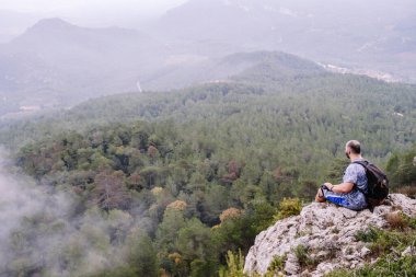 Yürüyüşçü dağın tepesindeki manzaraya hayran..