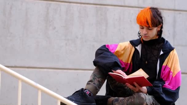 Mladý Muž Oranžovými Černými Vlasy Čte Červenou Knihu — Stock video