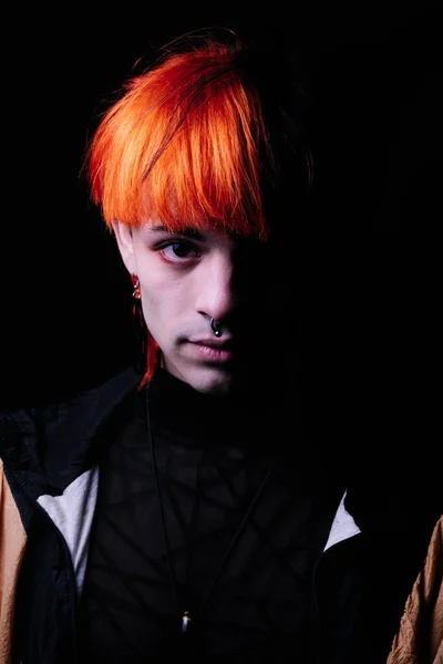 Close-up of boy with black and orange hair looking at camera.