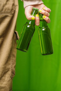 Elinde iki yeşil bira şişesi tutan bir kız..
