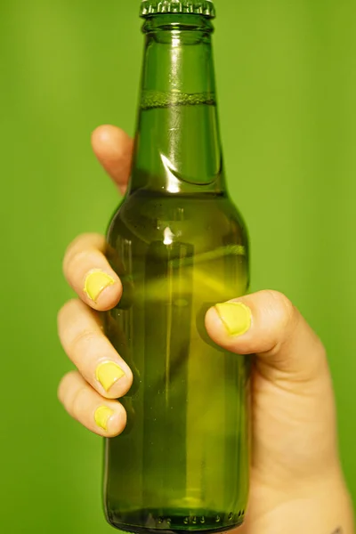 A girl holding a bottle of green beer.