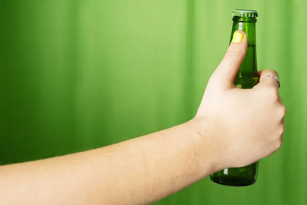 A girl holding a bottle of green beer.