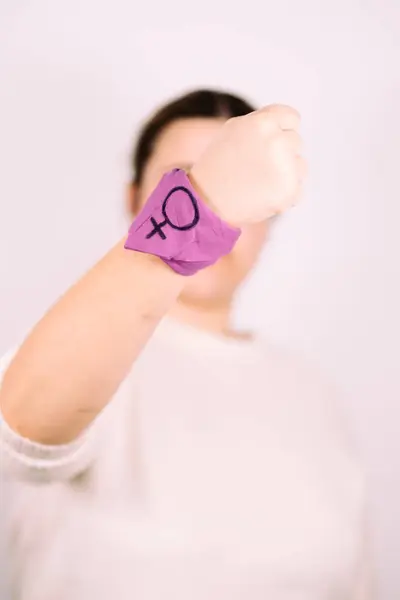 Feminist struggle concept. Woman with a purple scarf showing a raised finger.