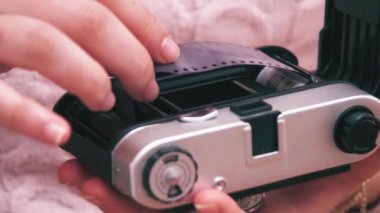 Pembe kazaklı kız analog kameraya film koyuyor..