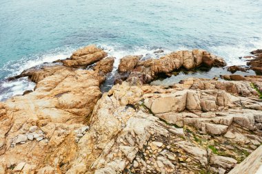 Kayaların üzerinde dalgalar koparken denize giren kayalar..