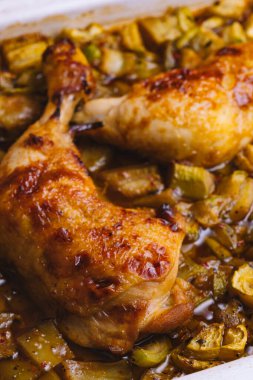 Fırında pişirilmiş tavuk butları ve tepside doğranmış sebzeler..