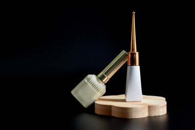 İki zarif kozmetik şişesi bir ahşap tezgahın üzerinde siyah bir arka plana karşı. Güzellik, cilt bakımı ya da lüks ürün temaları için mükemmel..