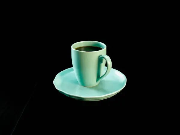 Nane yeşili kahve fincanının minimalist fotoğrafı, siyah kumaş arka planına yerleştirilmiş, uyumlu bir fincan tabağında. Sabah, kafein, minimalizm veya yaşam tarzı ile ilgili kavramlar için idealdir.