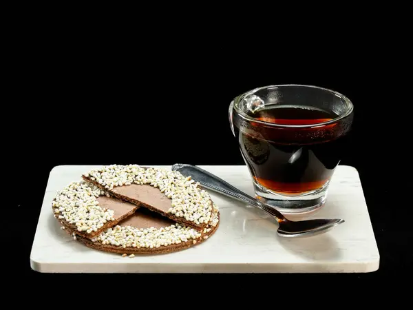 Bir bardak sıcak kahve geleneksel Meksika usulü çikolatayla eşleştirildi ve beyaz mermer bir tahtada siyah bir fonda duran kaşık ile pofuduk amaranth kurabiyesi. Yemek fotoğrafçılığı, kültür mutfağı ve sıcak içecek temaları için mükemmel.