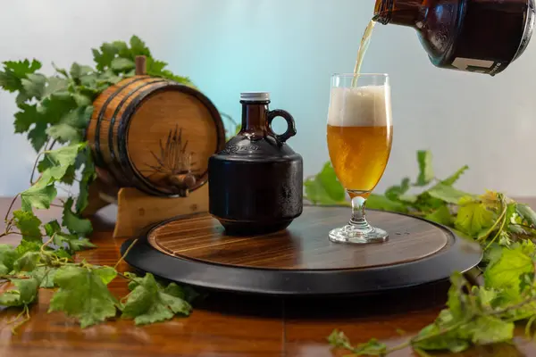 Bira ve şerbetçiotlu bira bardağı, yanında 32 onsluk homurtu ve agave oymalı mini yaşlanma fıçısı, doğal ve sanatsal bir hissi çağrıştırıyor..