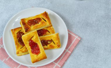 Ortasında çilek reçeli olan hamur işi beyaz bir tabakta servis edilir. Çilekli Fransız turtası. Tarif, makale, katalog ya da herhangi bir ticari amaç için mükemmel.