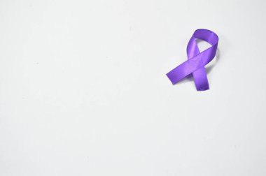 Tek bir mor kurdele temiz beyaz bir yüzeyde duruyor, sağda bir sürü boş alan bırakıyor. Dünya Lupus Günü Anması. Mor kurdele, pankreas kanseri için Mor kurdele ve Dünya Lupus Günü.