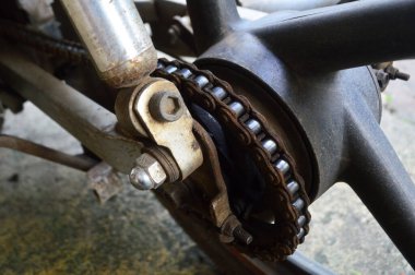 Paslı ve yağlı bir motosiklet zinciri ve viteslerin yakın çekimi. Motosiklet zinciri ve arka tekerlek dişlileri paslı ve kuru.