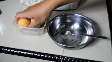 Kadının elleri mutfakta büyük bir yumurtayı bir kaseye kırıyor. Omlet pişirme, kahvaltı, öğle yemeği, sağlıklı yemek ve yemek pişirme kavramı. İki yumurta sarısıyla bir yumurta kıran eller, eşsiz yumurta.