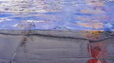 Güneşli bir günde havuz kenarında mavi havuz suyu, havuzun kenarında küçük dalgalar.