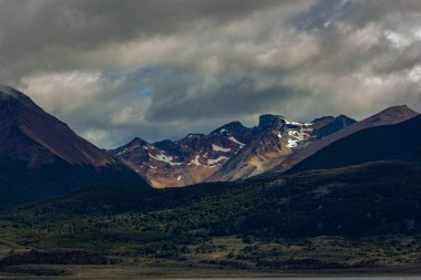 Ushuaia, Arjantin yakınlarında güneş ışığı, dağlar ve bulutlarla dramatik bir manzara.